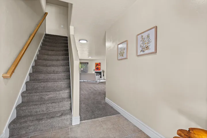 Carpeting on staircase and lower level, tile flooring in entryway, and a built-in overhead light fixture