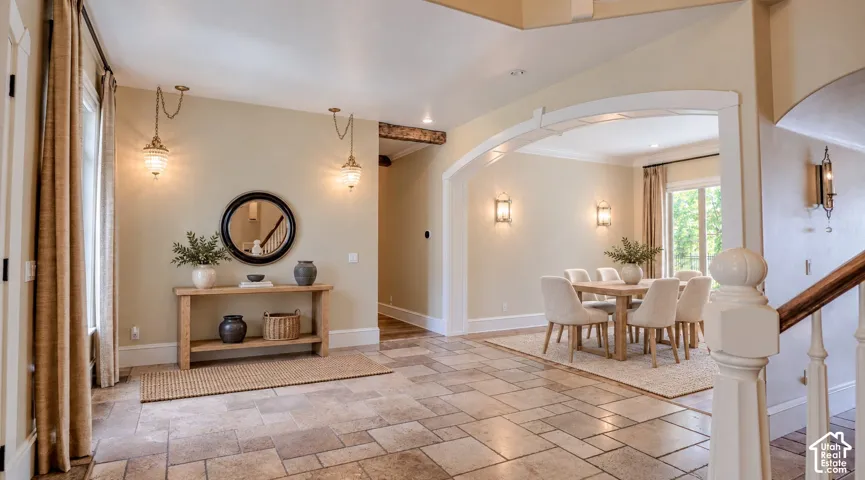 Foyer featuring large-format tile flooring, a decorative arched entryway, and custom wall-mounted lantern lighting