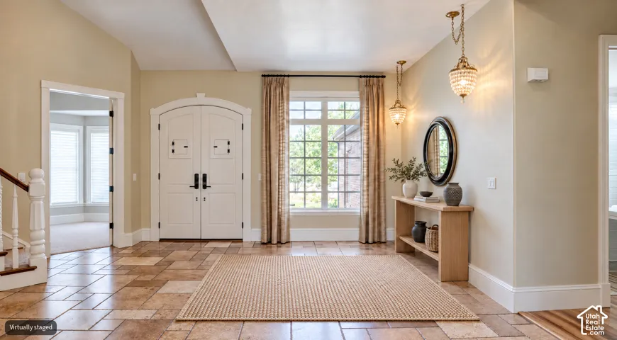 Arched double-door entry with dark hardware, tile flooring, two decorative pendant lights, and a window with curtains