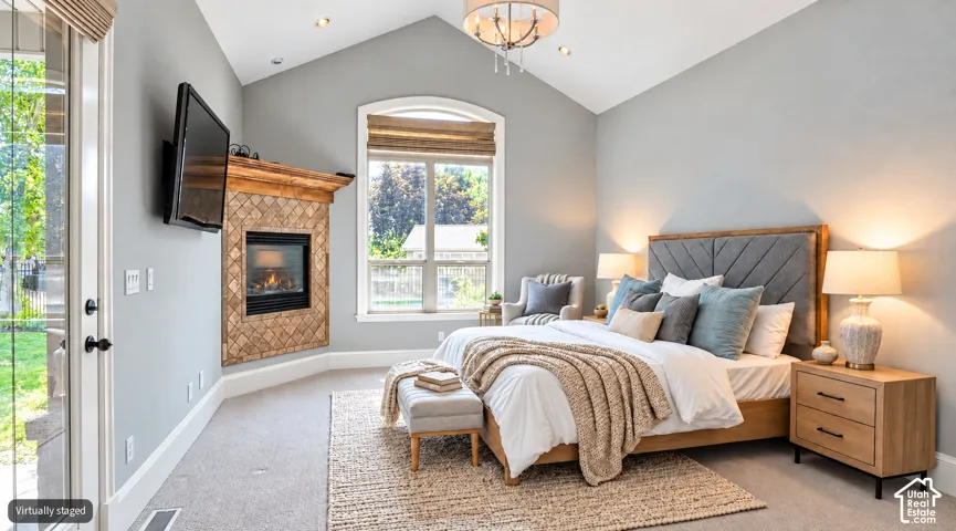 Vaulted ceiling in primary bedroom, arched window, tiled fireplace with wood mantel, and glass-paneled exterior door