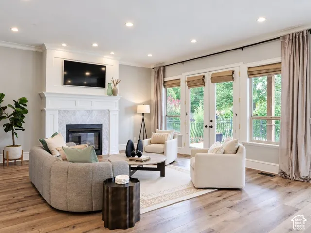 Recessed lighting, wood-finish flooring, white trim, and a fireplace with a light-toned surround