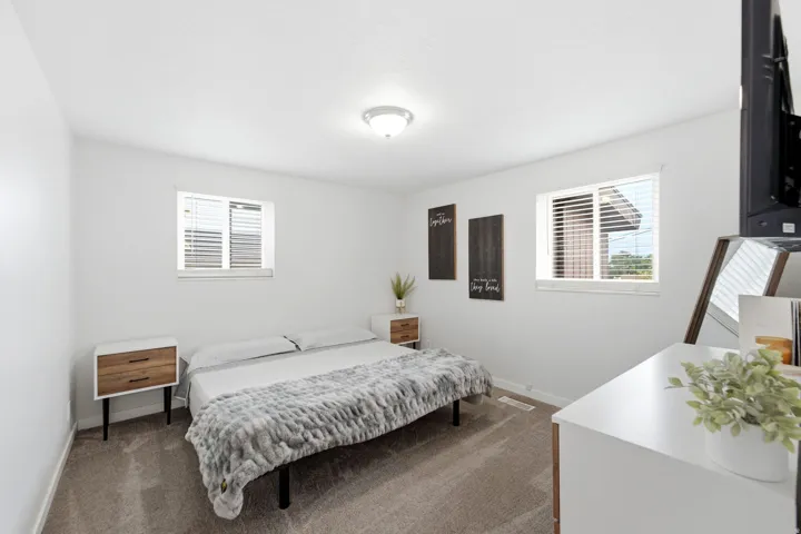 Ceiling lighting, light-colored walls, dual windows with blinds, and neutral carpeting