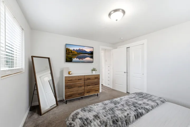 Bright primary bedroom featuring neutral wall finishes, carpet, and abundant natural light from dual windows
