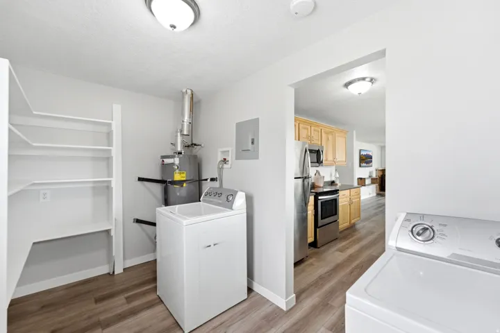 Dedicated utility area featuring wood-finish flooring, built-in shelving, and neutral wall paint