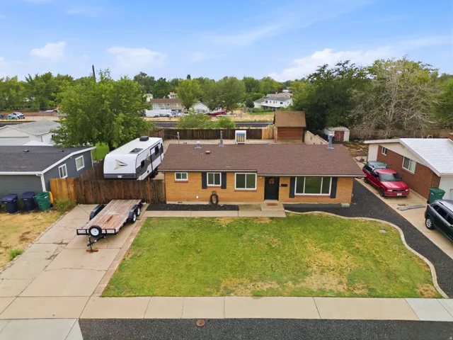 Brick ranch home featuring a spacious front lawn with single-car driveway and RV parking