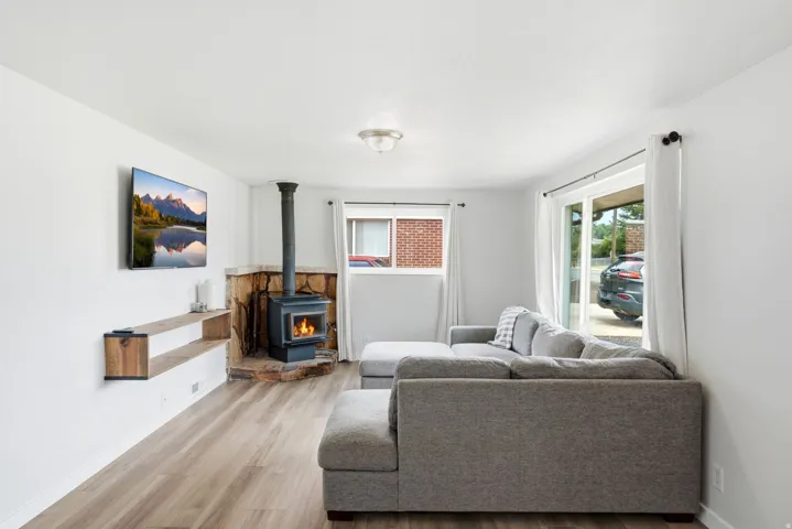 Wood-finish flooring throughout, a stone-faced wood-burning stove, and built-in floating shelves