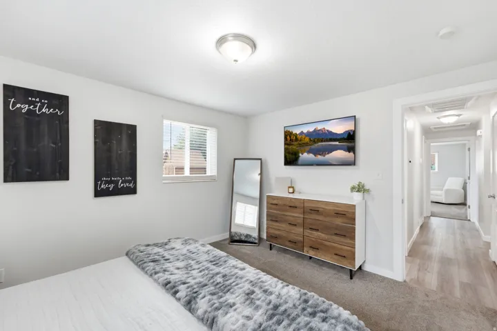 Bright primary bedroom featuring neutral wall finishes, carpet, and abundant natural light from dual windows