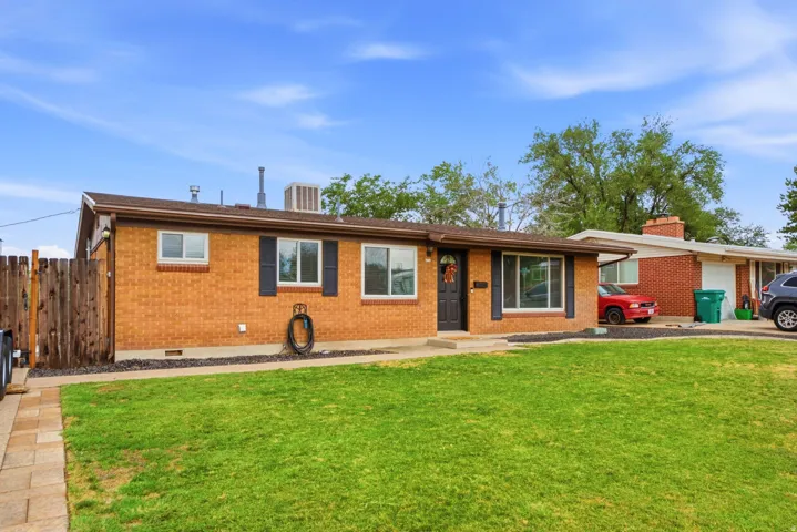 Brick exterior with a brown shingle roof, black shutters, and a wood privacy fence