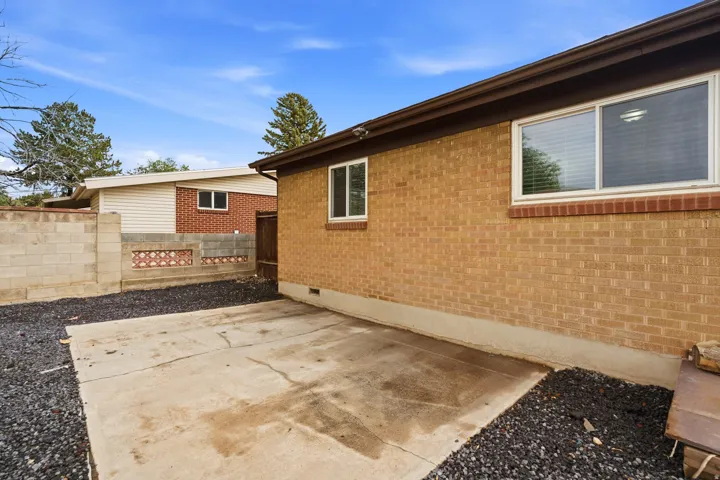 Brick exterior with sliding windows, concrete patio, and dark gravel landscaping