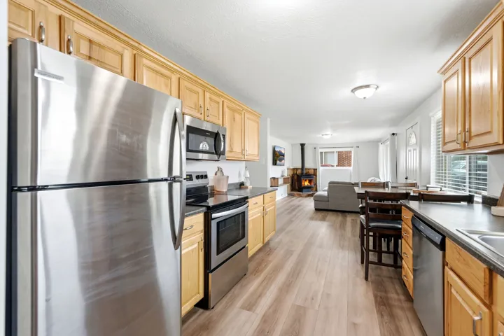 Kitchen featuring stainless steel appliances, wood-finish flooring, and light wood cabinetry