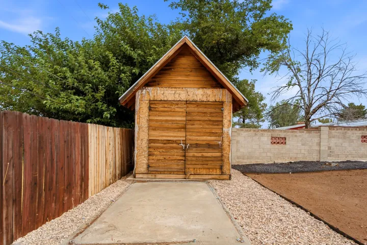 Wood-sided shed with double doors, concrete pad, and gravel surround