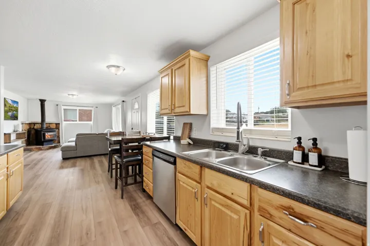 Kitchen featuring wood-finish cabinetry, stainless steel double basin sink, and stainless steel dishwasher