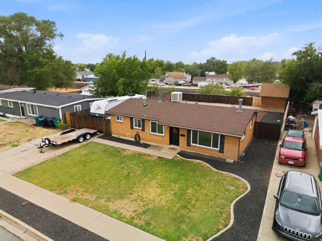 Brick exterior with a brown shingle roof, complemented by a front yard with a lawn and gravel landscaping