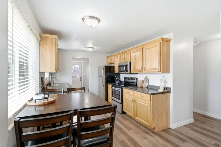 Kitchen with wood-finish flooring, natural wood cabinetry, stainless steel appliances, dark countertops