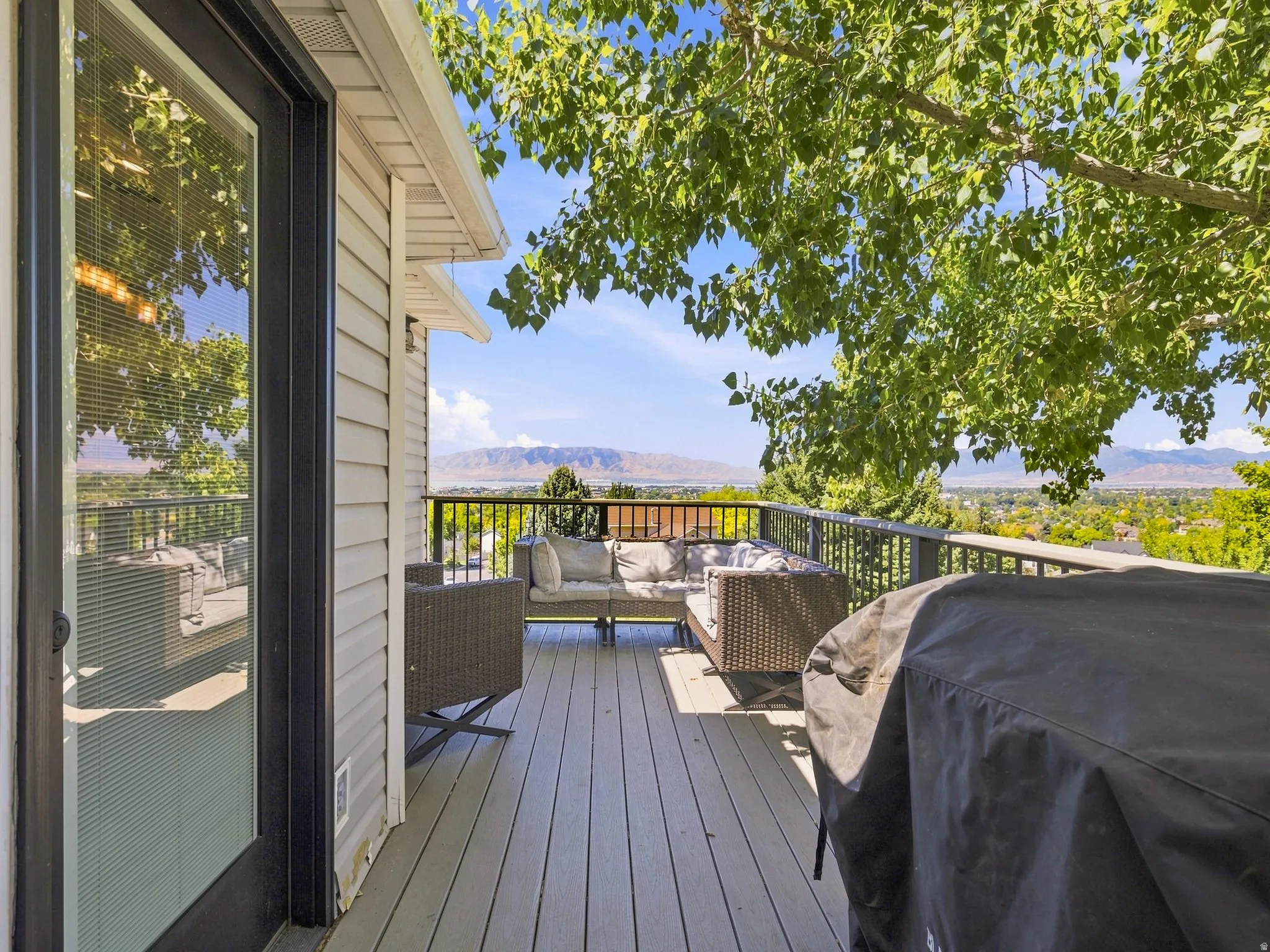 Outdoor deck with composite plank flooring, black metal railings, and mountain scenery