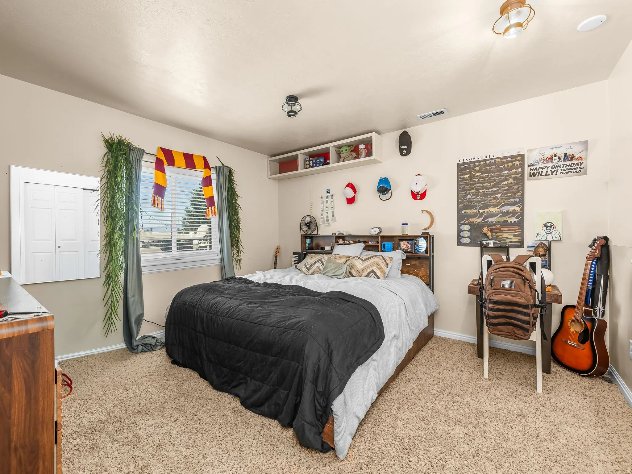 Neutral wall paint, ceiling-mounted light fixtures, carpet flooring, a window with blinds, and white bi-fold closet doors