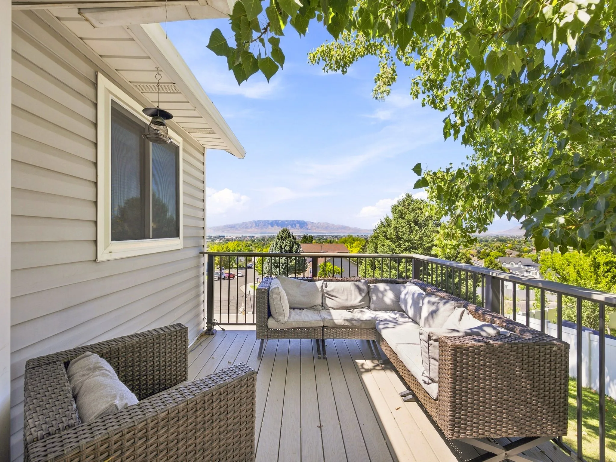 Outdoor deck with composite decking and black metal railings, featuring mountain scenery