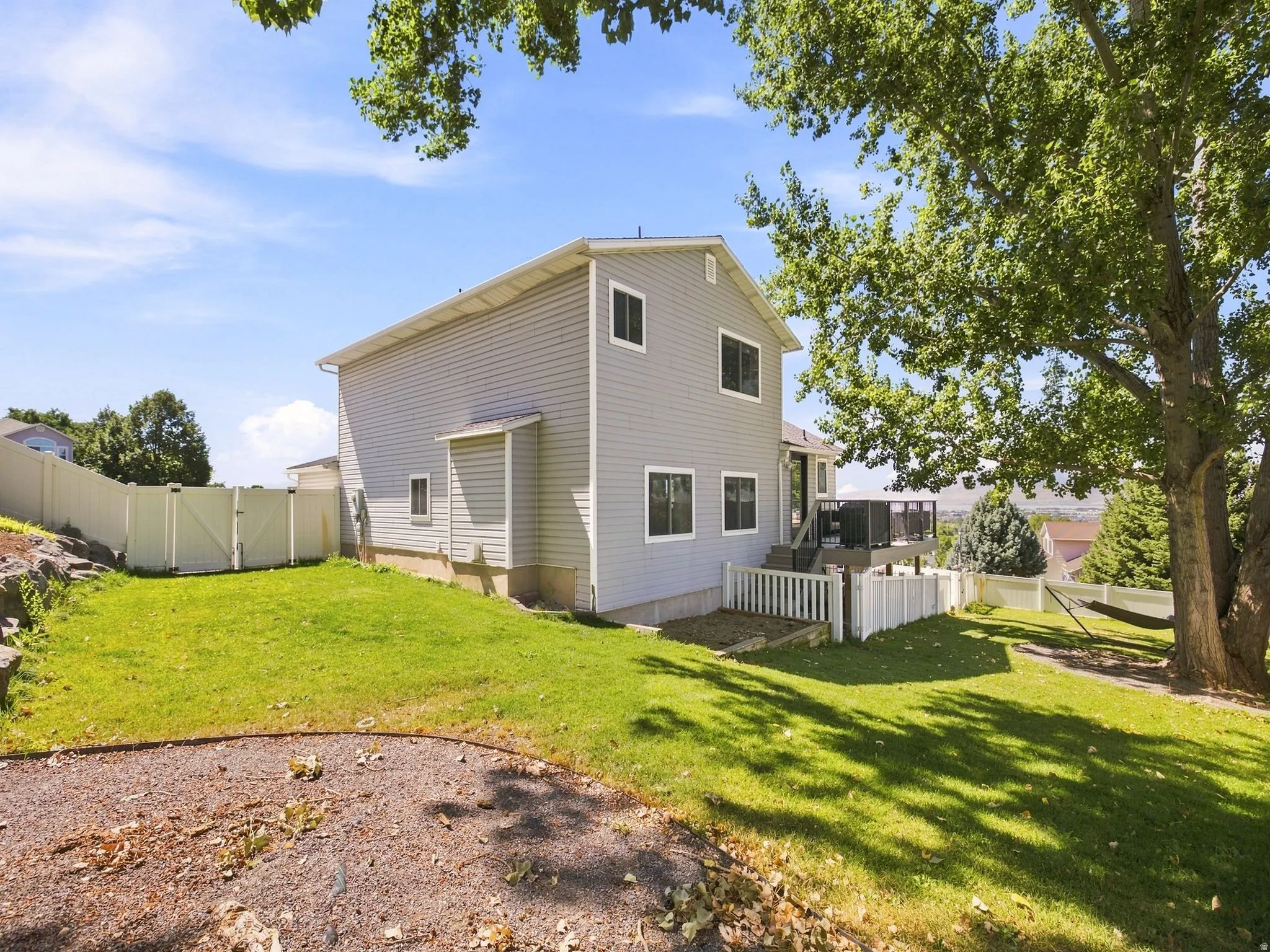 Rear exterior with light gray siding, multiple windows, and a raised deck with dark railings