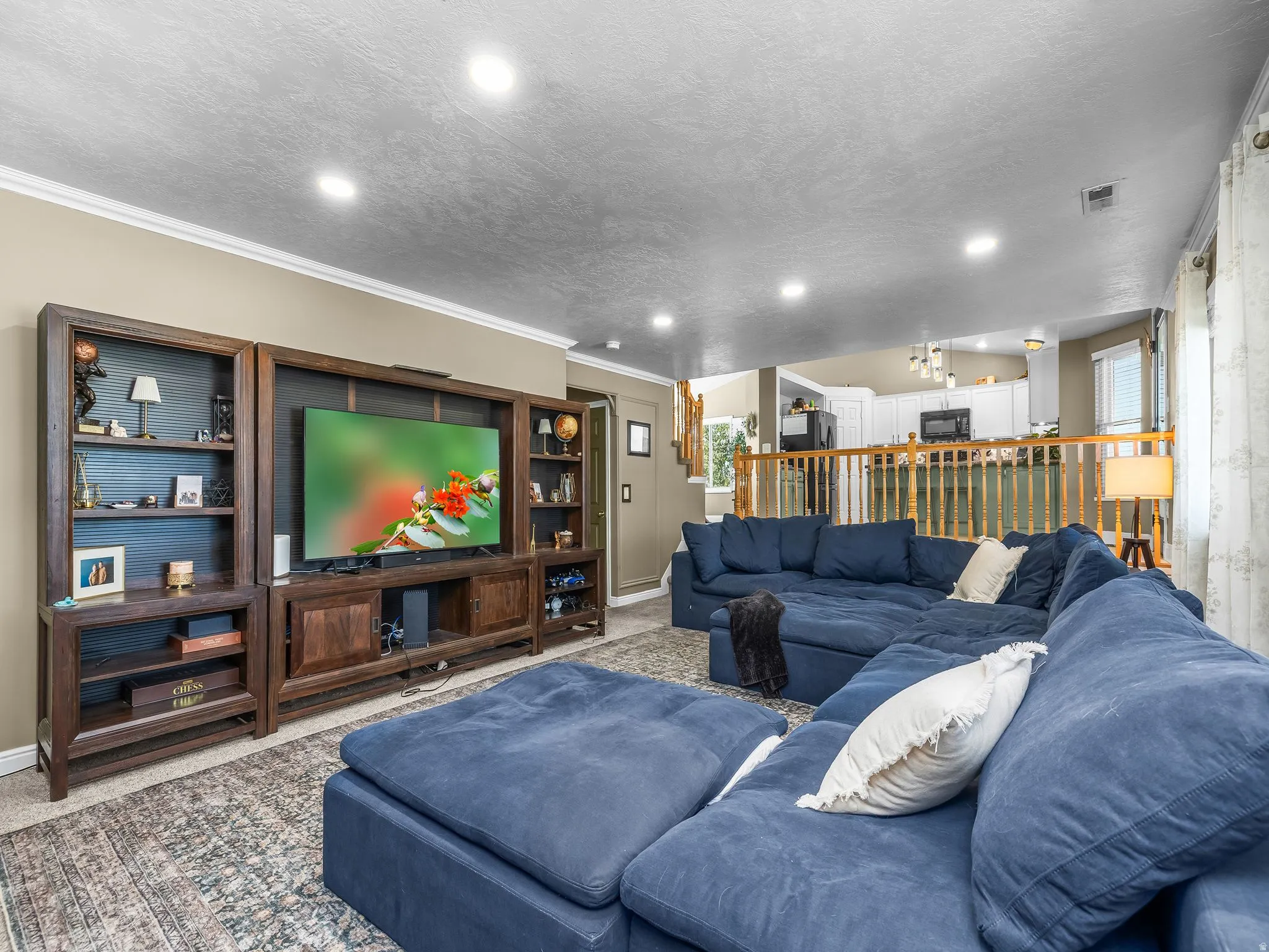 Built-in media center with shelving, recessed lighting, crown molding, open concept design, and hardwood railing