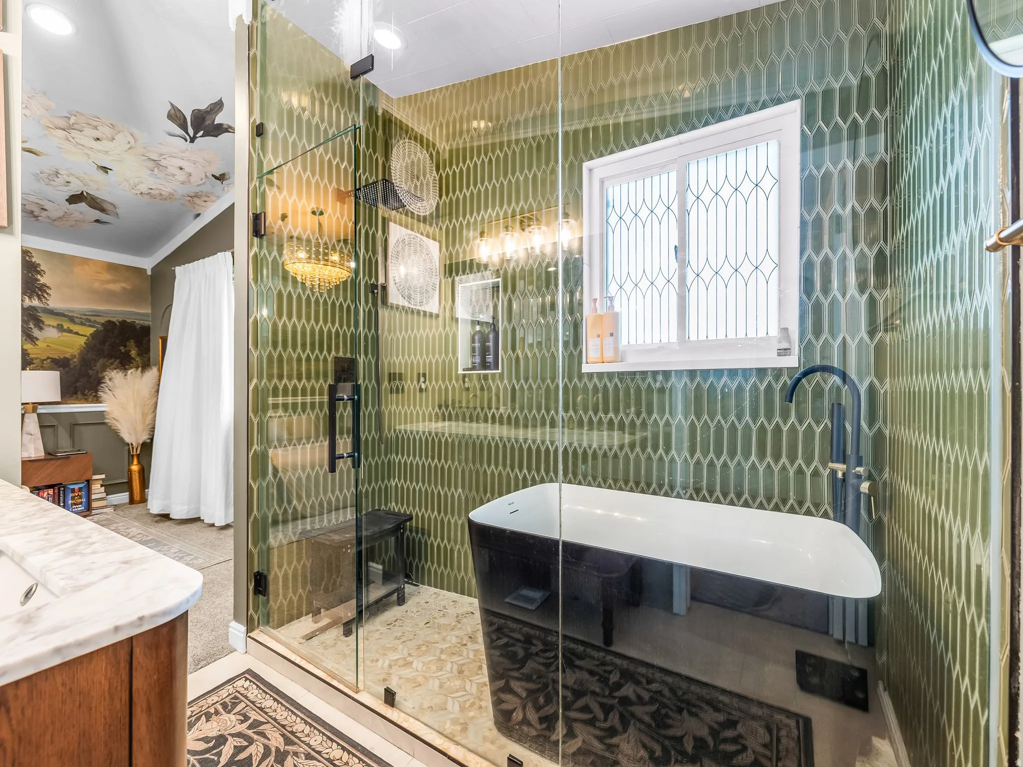 Glass-enclosed shower with green picket tile, freestanding soaking tub, and decorative window
