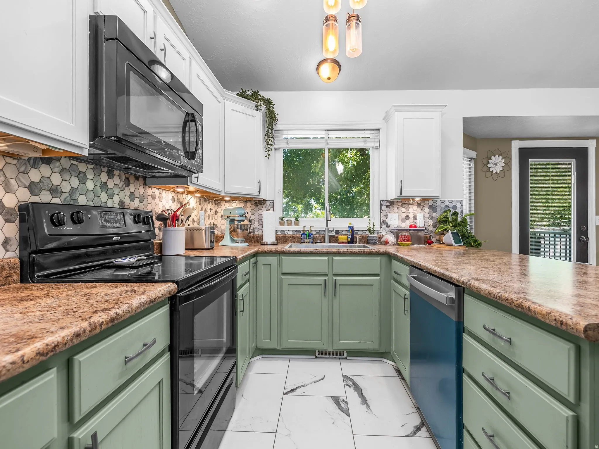 U-shaped kitchen featuring white upper cabinetry, green lower cabinetry, and a patterned tile backsplash