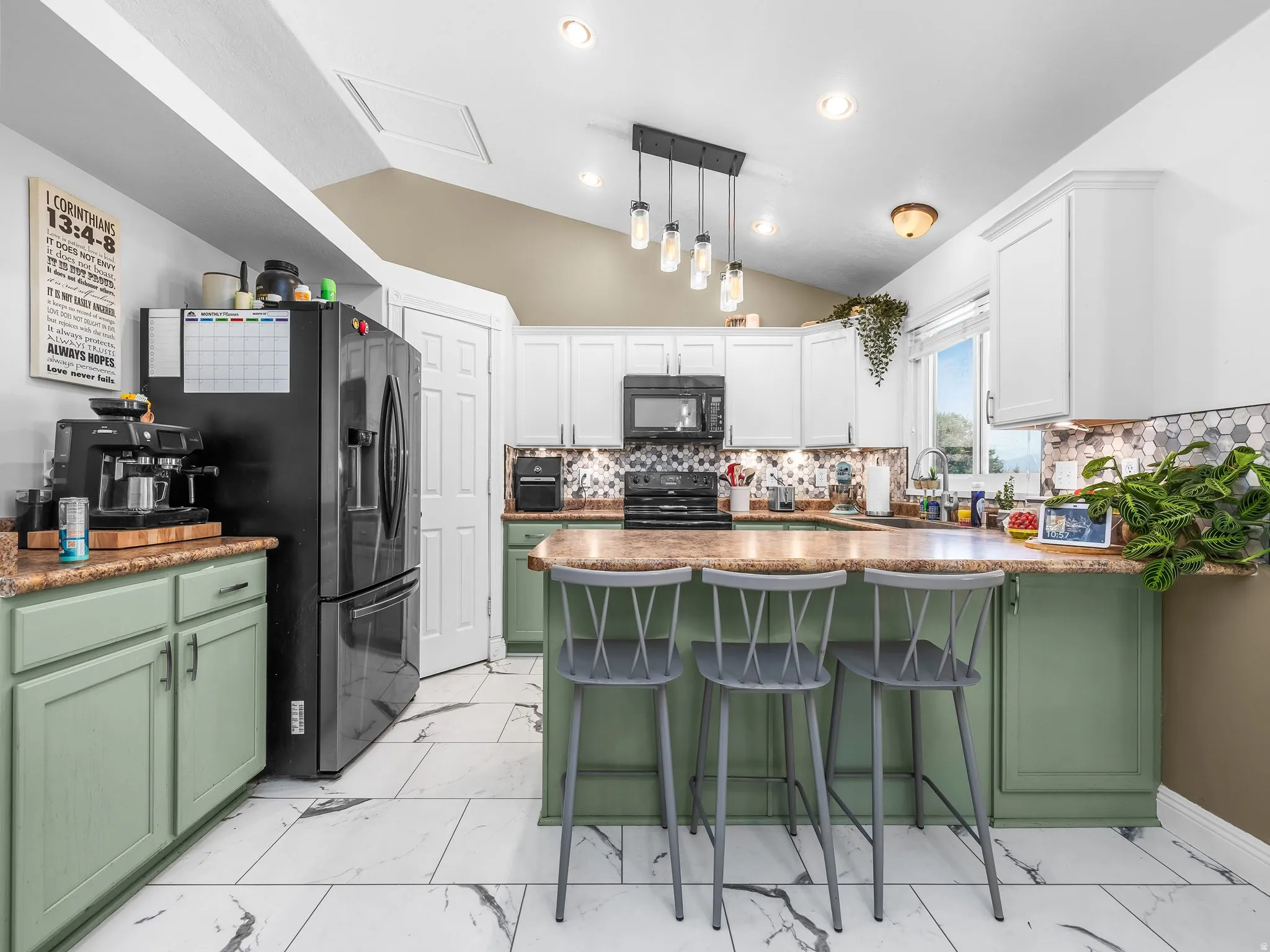 Kitchen featuring white upper cabinetry, green lower cabinetry, a hexagonal tile backsplash, a kitchen island with seating, and wood-finish flooring