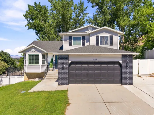Two-story exterior with light gray siding, dark brick accents, and a dark asphalt shingle roof