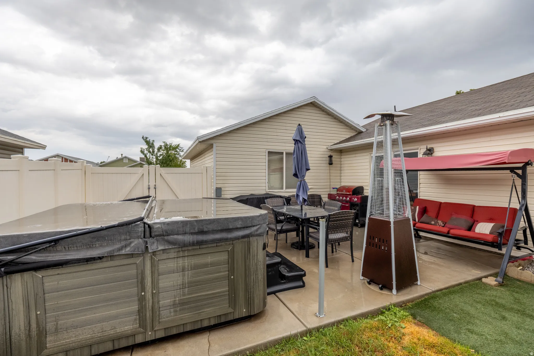 Beautifully maintained exterior featuring a manicured lawn, light-colored siding, white vinyl and black metal fencing, and a large custom-built storage shed with double doors providing ample additional storage.