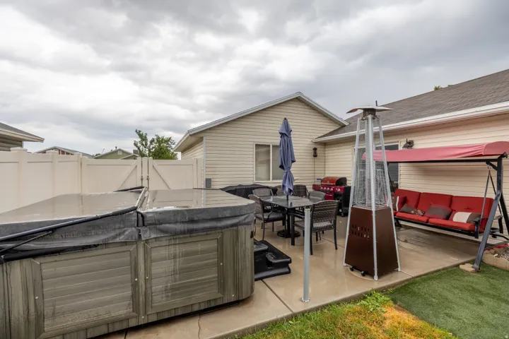 Beautifully maintained exterior featuring a manicured lawn, light-colored siding, white vinyl and black metal fencing, and a large custom-built storage shed with double doors providing ample additional storage.