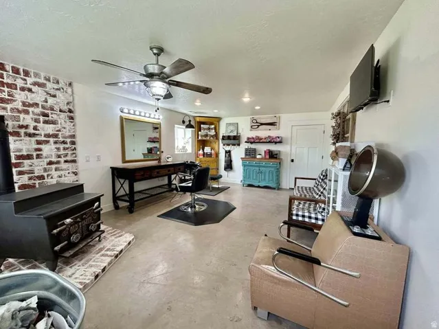Exposed brick accent wall, ceiling fan with integrated lighting, concrete flooring, and a white paneled door