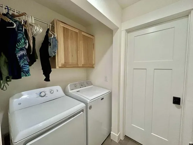 Wall-mounted wood-finish cabinetry, white three-panel door with matte black hardware, and an overhead hanging rod