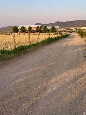 Dirt road access leading to multiple structures, including barns, with a mountain backdrop