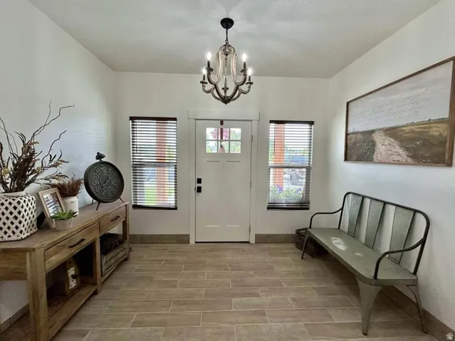 White entry door with decorative glass inserts, flanked by two windows with dark wood-finish blinds
