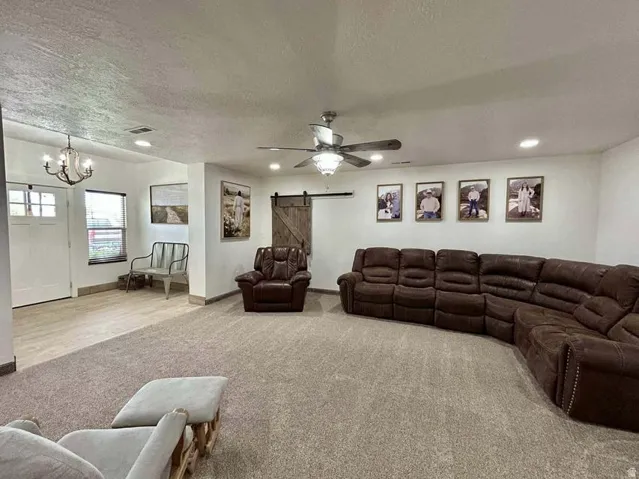 Recessed lighting, ceiling fan light fixture, wood-finish flooring, white walls, barn door