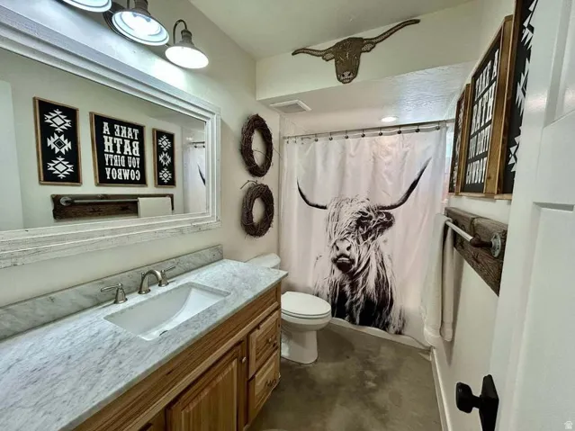 Vanity with a single undermount sink, brushed nickel faucet, light-toned wood cabinetry, and a light-colored stone countertop