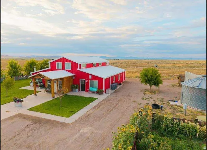 Red barn-style exterior with white trim, covered front porch with wood columns, separate entry, and a gravel driveway