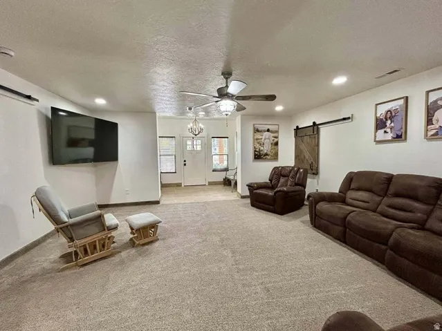 Recessed lighting, ceiling fan with light fixture, wood-finish flooring, white entry door with glass panels, and a barn-style sliding door