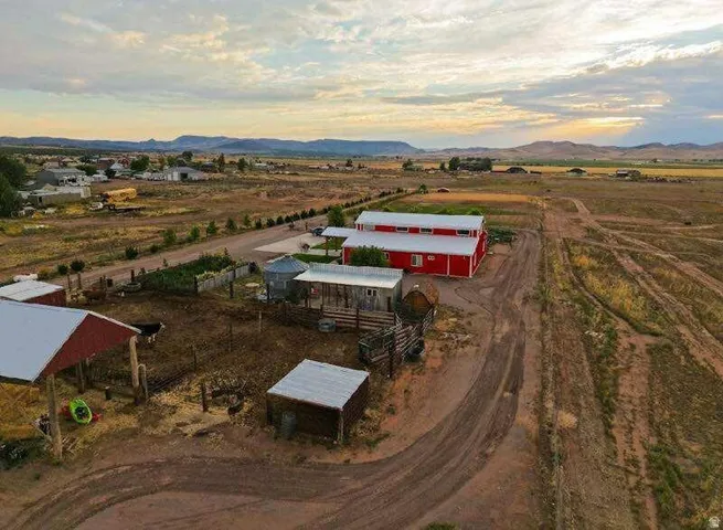 Red barn-style structure with white trim, multiple outbuildings, and expansive surrounding land
