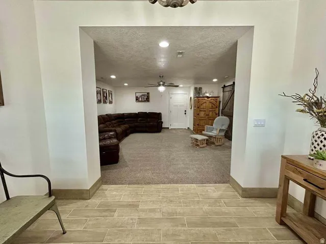 Spacious recreation room featuring recessed ceiling lighting, a ceiling fan, and neutral carpet flooring