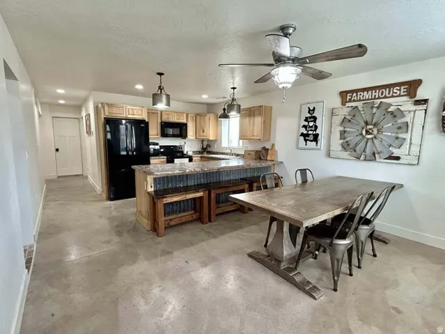 Spacious kitchen featuring wood cabinetry, black appliances, a central island with corrugated metal detailing, and recessed lighting
