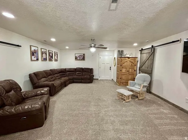 Recessed lighting, ceiling fan, white paneled door, wood barn door, and neutral-toned carpeting