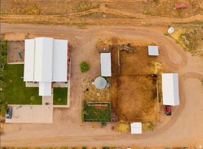 Main residence with metal roofing, multiple outbuildings, concrete patio, and a grassed yard area