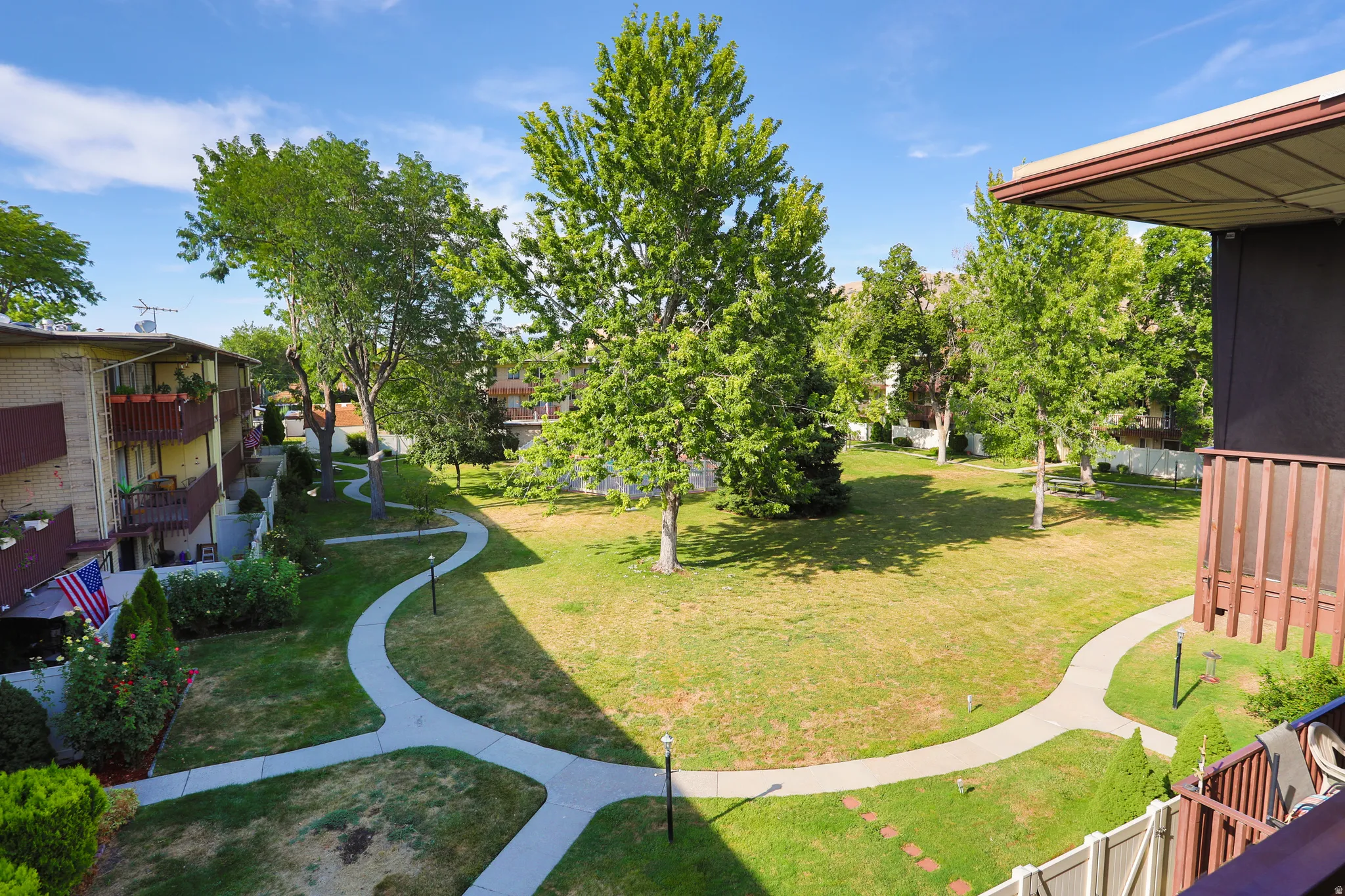 Expansive central green space with manicured lawn, established trees, and winding pedestrian pathways