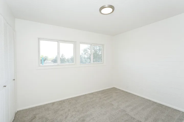 Plush grey carpeting, dual windows, integrated ceiling light fixture, and bifold closet doors