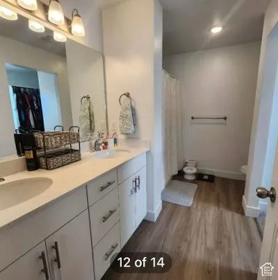 Dual vanity with undermount sinks, white cabinetry, and wood-finish flooring