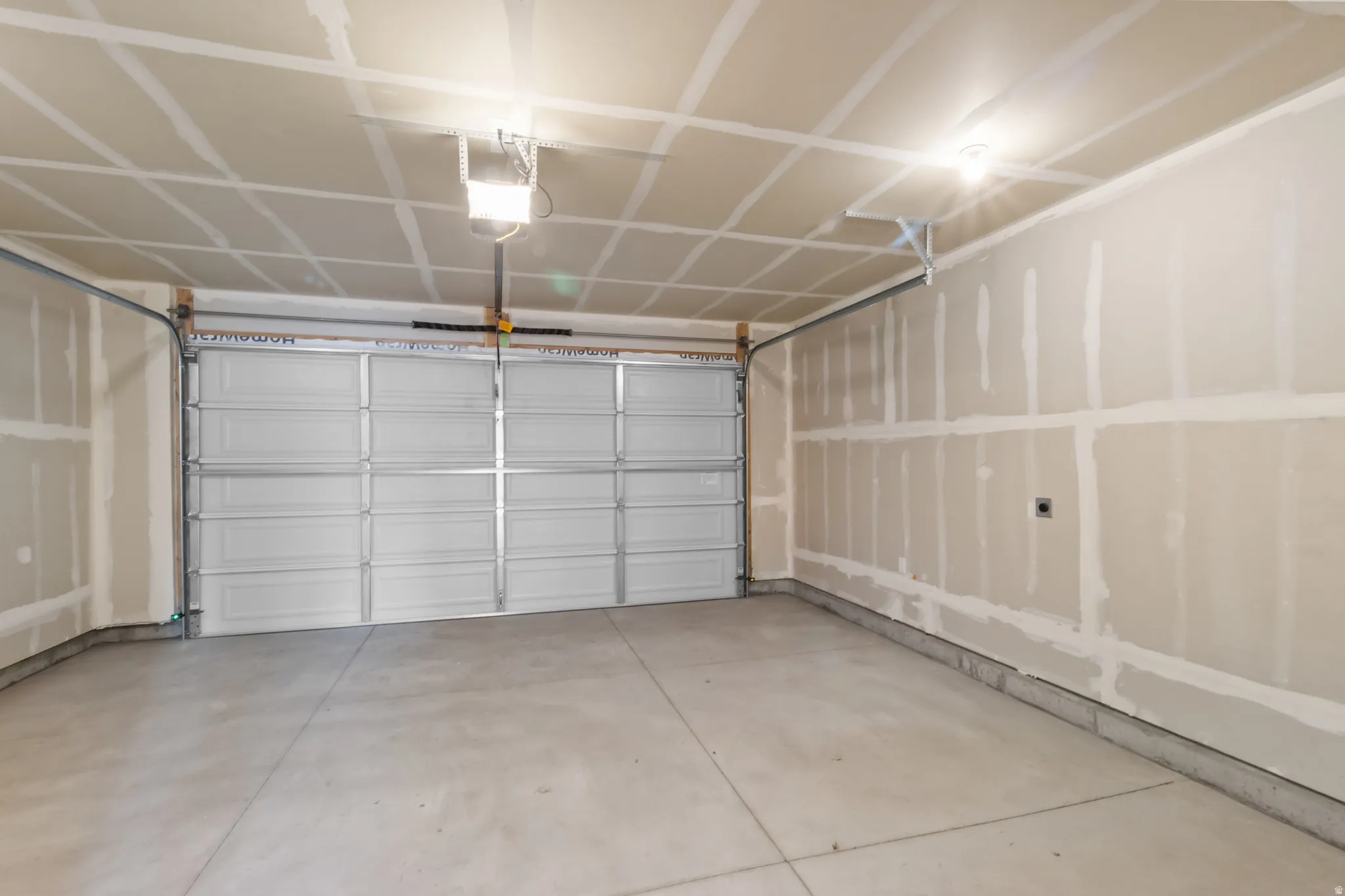 Concrete flooring, overhead lighting, and an automatic garage door opener