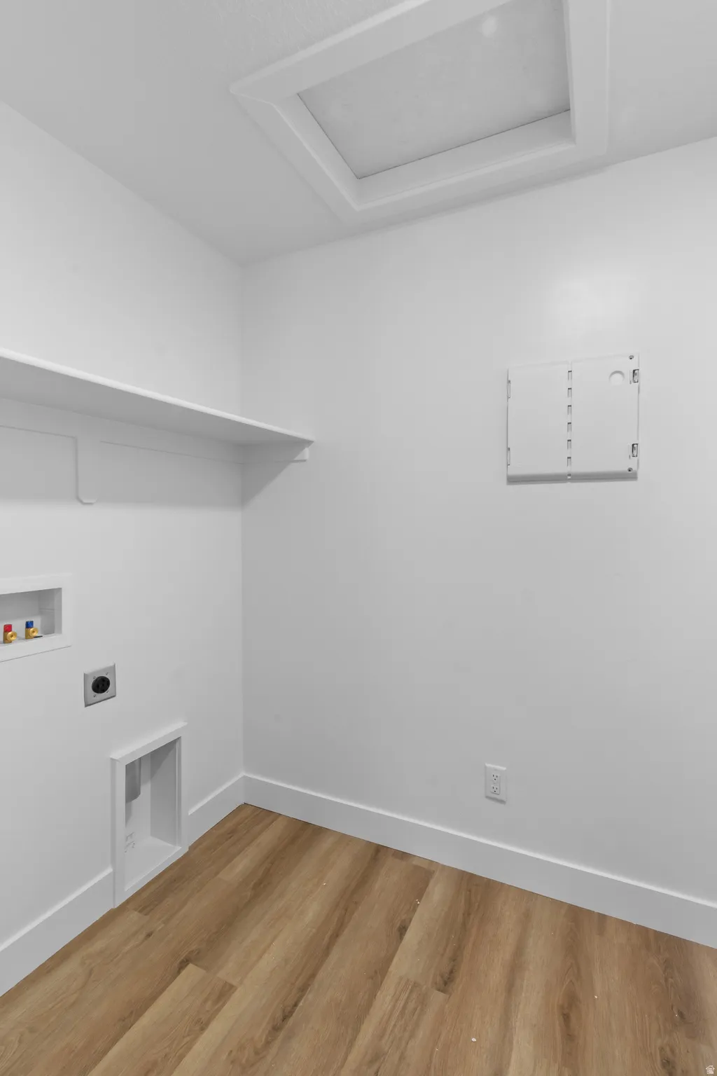 Recessed ceiling access panel, white wall shelving, wood-finish flooring, and white trim
