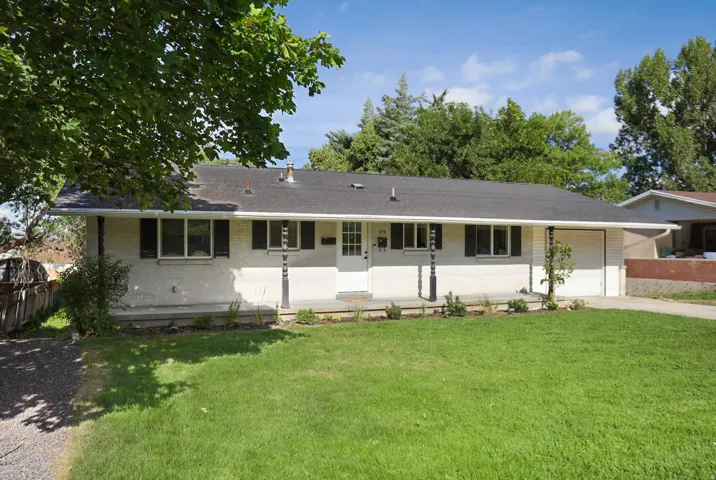 White brick exterior with a dark shingle roof, offering a covered front porch with decorative columns