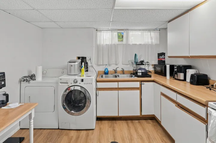 Laundry area featuring a front-load washer, a top-load dryer, and wood-finish flooring