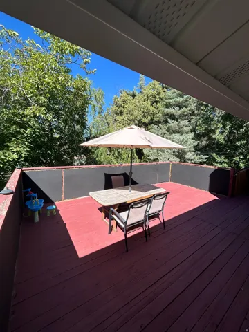 Spacious wood deck with dark red finish and partial overhead coverage